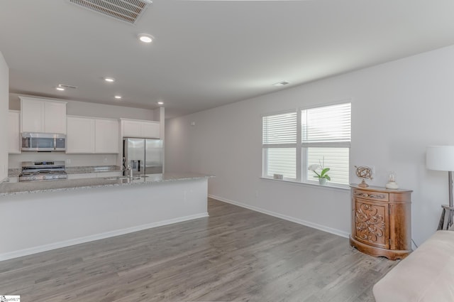 kitchen featuring baseboards, visible vents, light wood-style flooring, a sink, and appliances with stainless steel finishes