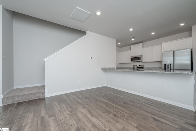kitchen with baseboards, recessed lighting, stainless steel appliances, wood finished floors, and white cabinetry