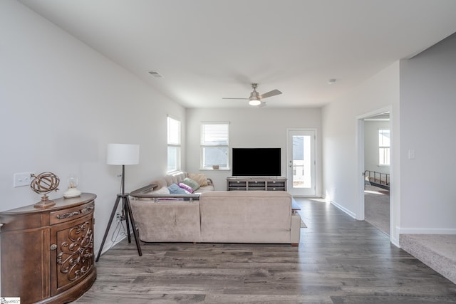 living area with baseboards, wood finished floors, visible vents, and ceiling fan
