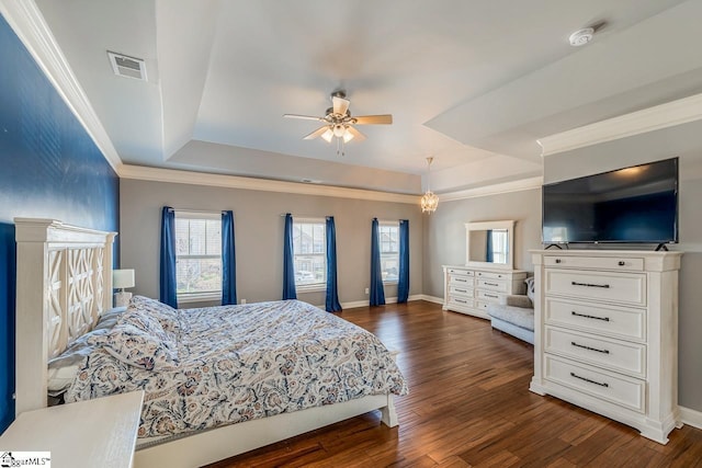 bedroom with a tray ceiling, dark wood-style floors, visible vents, and ornamental molding
