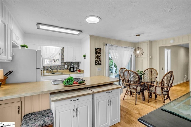 545 Long Reach Dr, Salem, SC 29676 - kitchen with white cabinetry, freestanding refrigerator, decorative light fixtures, light wood-style floors, and a sink