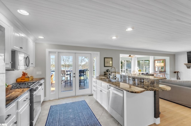 kitchen with a sink, open floor plan, white cabinetry, and stainless steel appliances