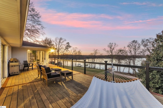 deck at dusk featuring a water view
