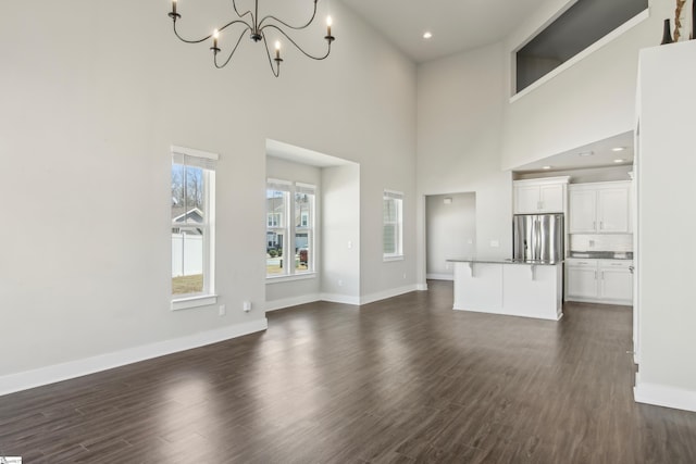 31 Creekhaven Ln, Taylors, SC 29687 - unfurnished living room with an inviting chandelier, baseboards, and dark wood-style flooring