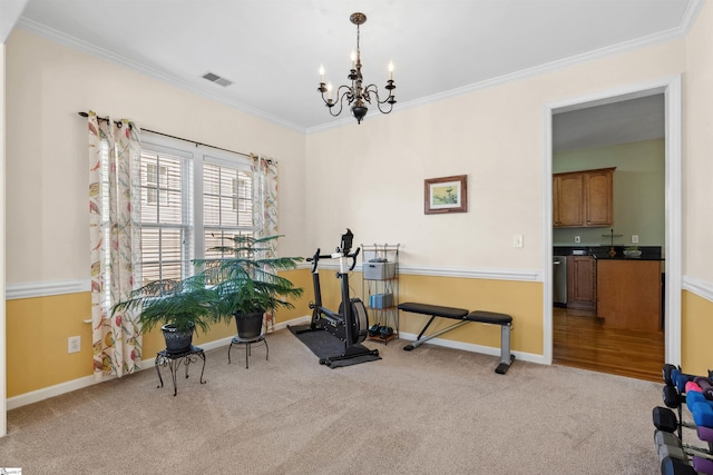 workout area featuring visible vents, carpet floors, a notable chandelier, and ornamental molding