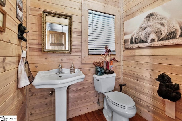 bathroom featuring wood walls, toilet, and wood finished floors