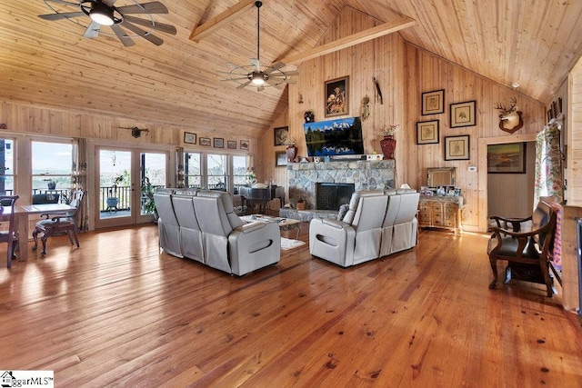 living room with wooden walls, wood ceiling, a fireplace, and a ceiling fan