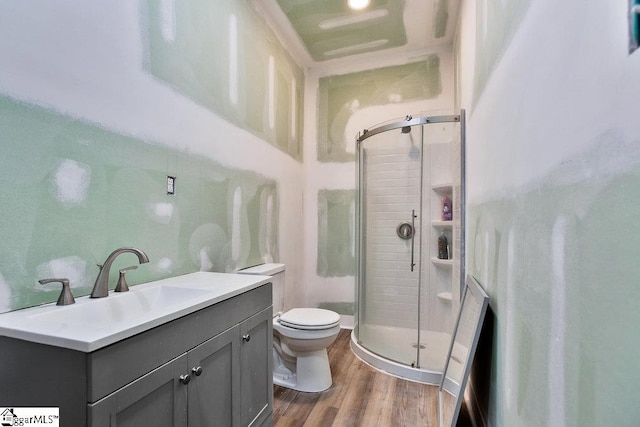 bathroom featuring vanity, toilet, wood finished floors, and a shower stall