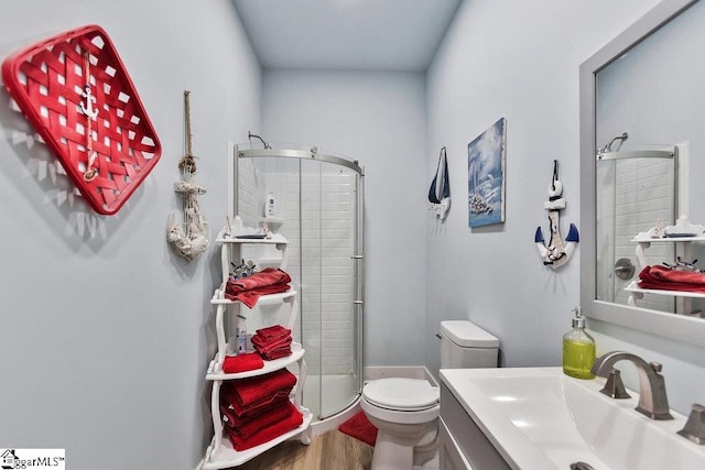 bathroom featuring a stall shower, toilet, vanity, and wood finished floors