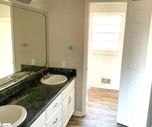 bathroom with visible vents, a sink, double vanity, and wood finished floors