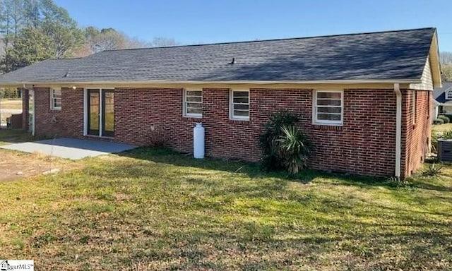 rear view of house with brick siding, a yard, and a patio