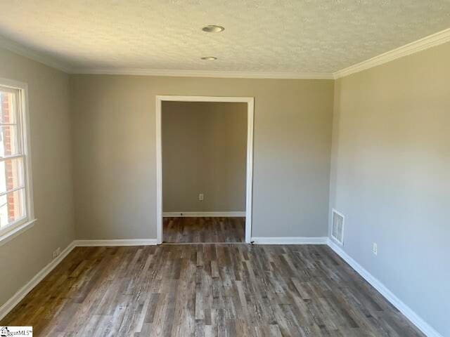 unfurnished room featuring wood finished floors, plenty of natural light, baseboards, and visible vents