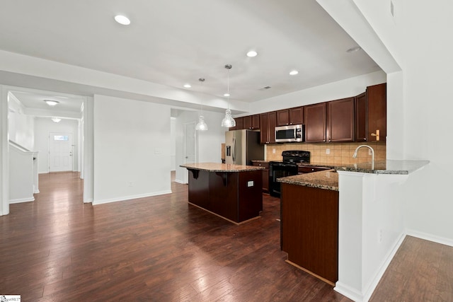 kitchen with stone counters, dark wood-style flooring, a breakfast bar, decorative backsplash, and stainless steel appliances