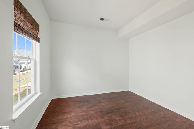spare room featuring baseboards, dark wood finished floors, visible vents, and a wealth of natural light