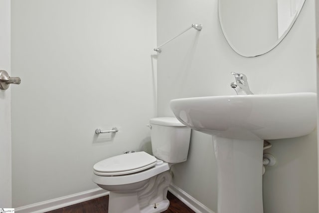 bathroom with toilet, wood finished floors, and baseboards