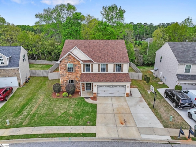 traditional-style house featuring a front yard, fence, an attached garage, a shingled roof, and concrete driveway