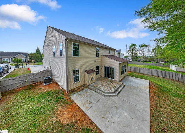 back of house with central air condition unit, a yard, a fenced backyard, a patio area, and a gate