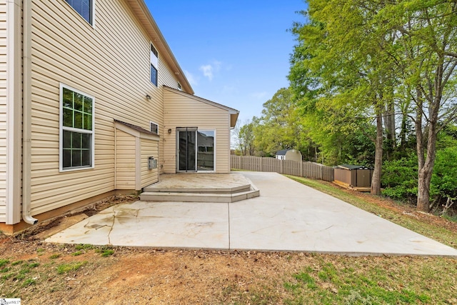 rear view of property featuring an outdoor structure, fence, a patio, and a shed