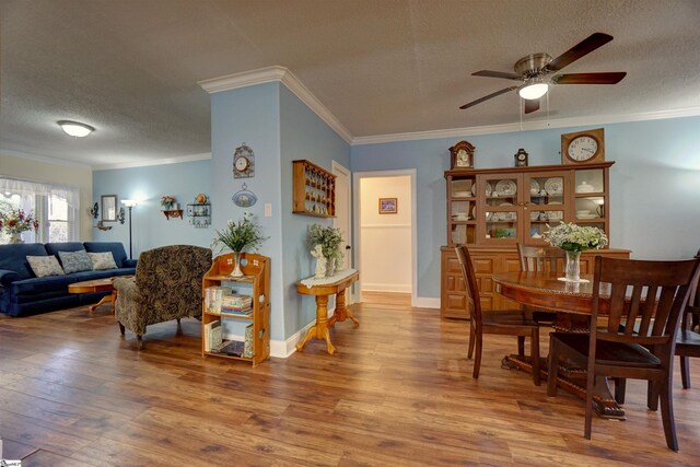 dining space with ornamental molding, baseboards, a textured ceiling, a ceiling fan, and wood finished floors