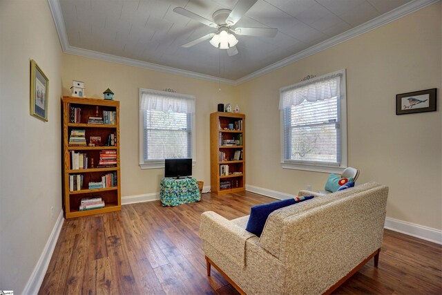 living area featuring baseboards, wood finished floors, ornamental molding, and a ceiling fan