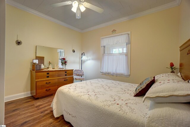 bedroom featuring baseboards, a ceiling fan, wood finished floors, and crown molding