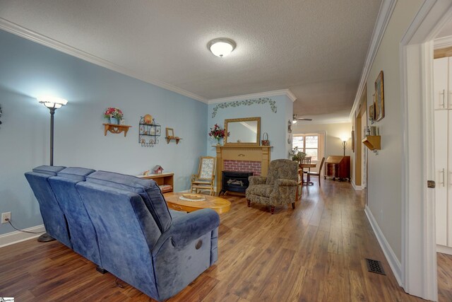 living area featuring a tile fireplace, wood finished floors, a textured ceiling, visible vents, and ornamental molding