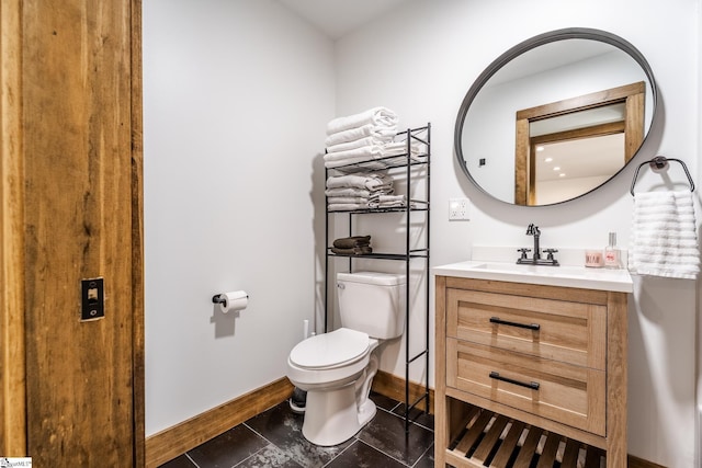 half bath with baseboards, toilet, and vanity
