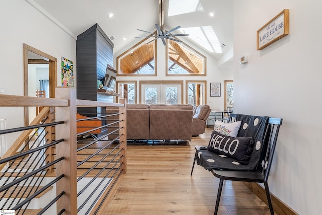 sitting room with an upstairs landing, high vaulted ceiling, baseboards, light wood finished floors, and a ceiling fan