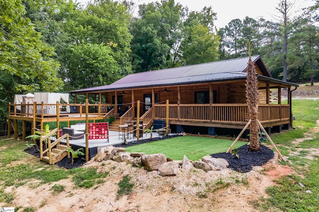 cabin with metal roof, a front yard, a deck, log siding, and a patio area