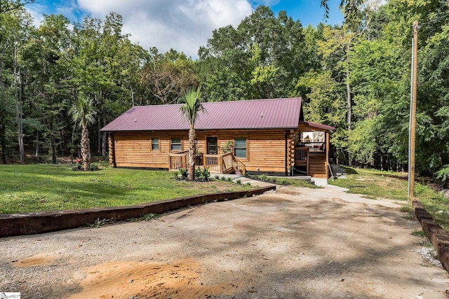 log home with log siding, a front yard, a view of trees, and metal roof