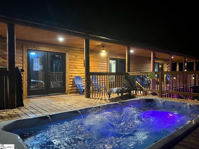 pool at twilight featuring an outdoor hot tub and a deck