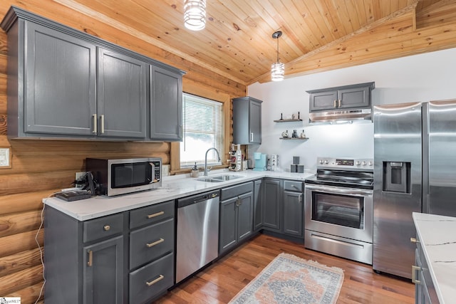 kitchen with stainless steel appliances, under cabinet range hood, a sink, gray cabinetry, and vaulted ceiling