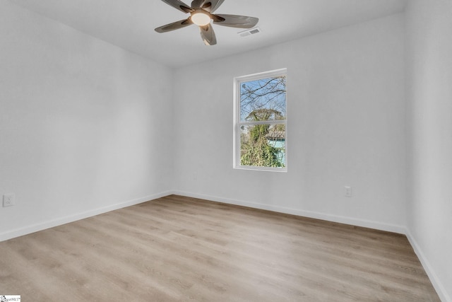 empty room featuring baseboards, ceiling fan, visible vents, and light wood-style flooring