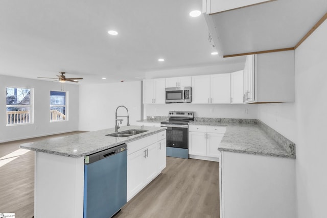 kitchen with a sink, white cabinets, light wood finished floors, stainless steel appliances, and recessed lighting