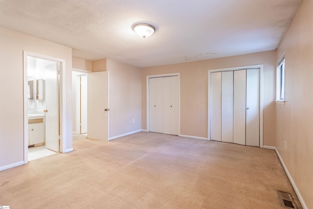 unfurnished bedroom with baseboards, carpet floors, and two closets