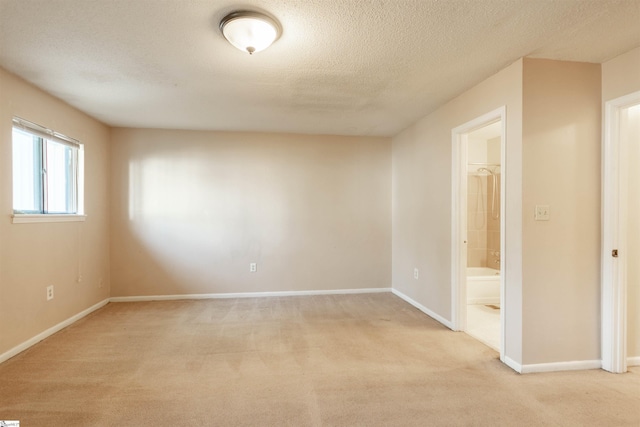 unfurnished room featuring baseboards, a textured ceiling, and light carpet