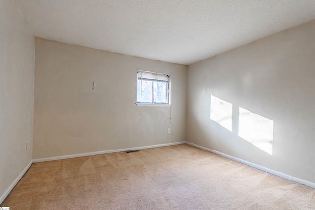 empty room with baseboards, carpet floors, a textured ceiling, and visible vents