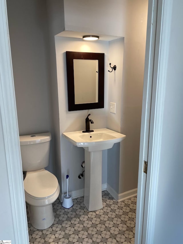 half bathroom with baseboards and toilet