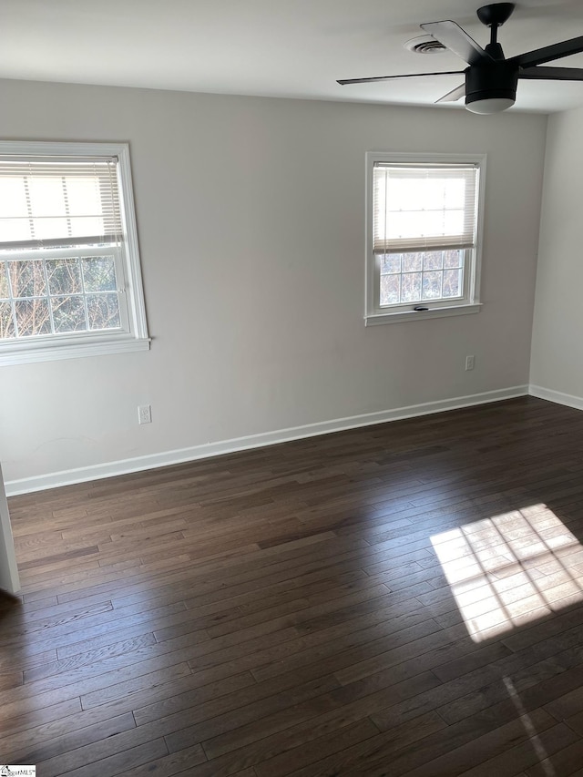 spare room with baseboards, dark wood-style flooring, visible vents, and a ceiling fan