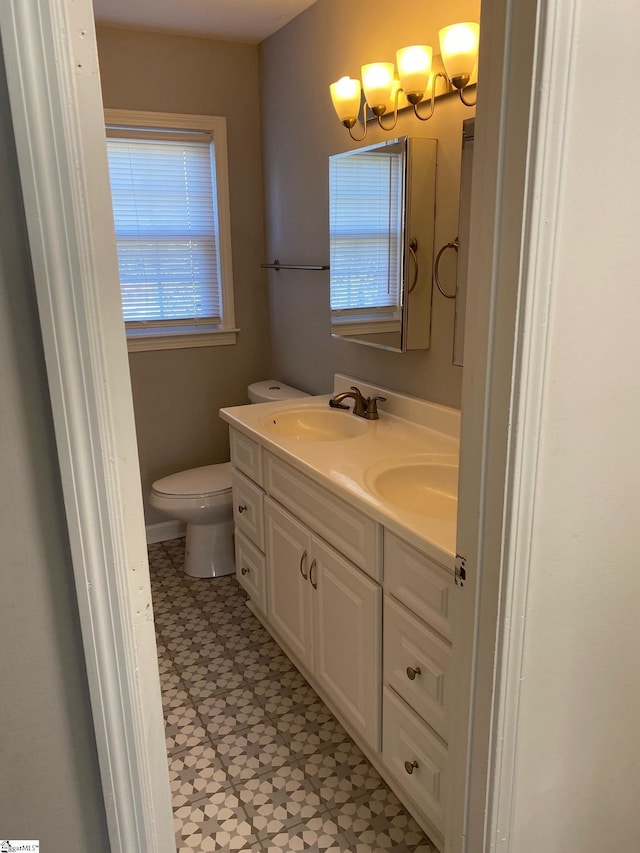 bathroom featuring double vanity, a sink, tile patterned floors, and toilet