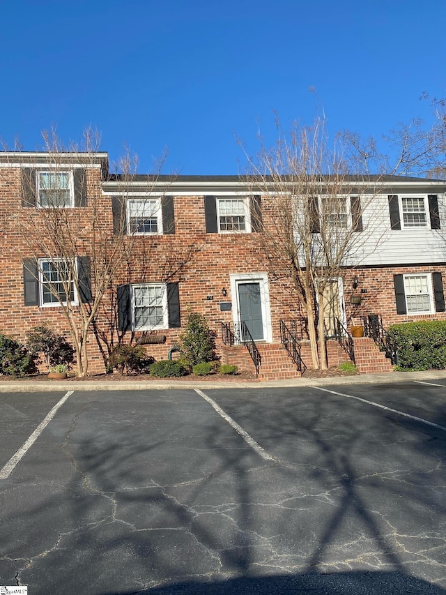 view of front facade with uncovered parking and brick siding