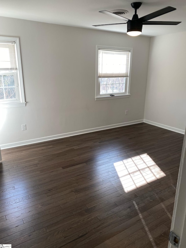 unfurnished room featuring dark wood-style floors, visible vents, baseboards, and a ceiling fan