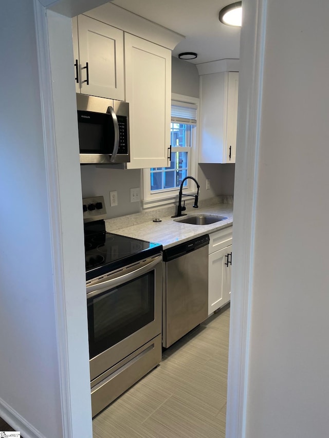 kitchen with white cabinetry, a sink, light countertops, and appliances with stainless steel finishes