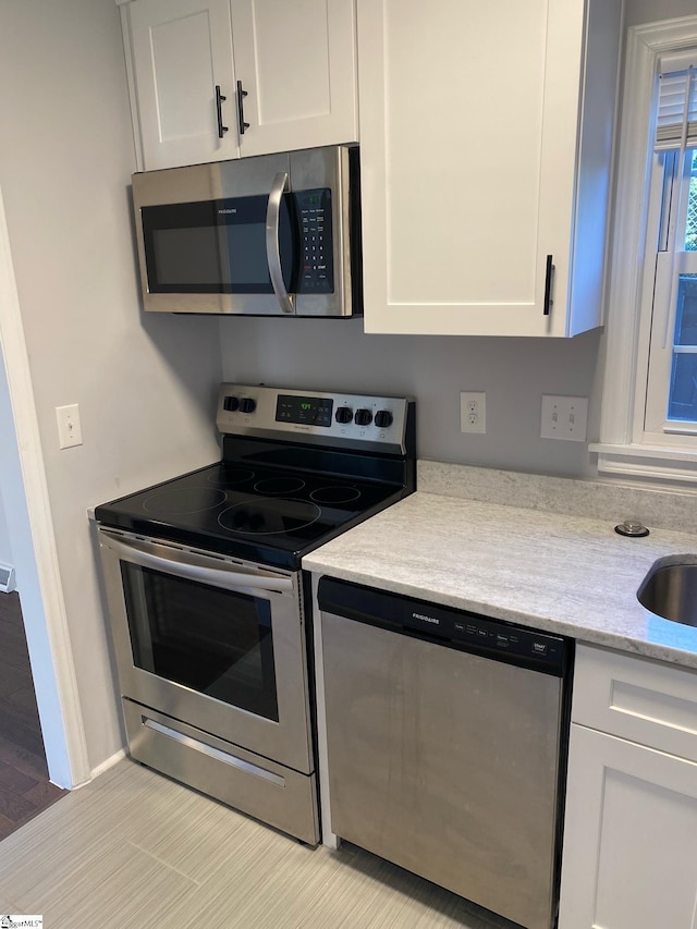 kitchen with white cabinets, light stone countertops, and stainless steel appliances
