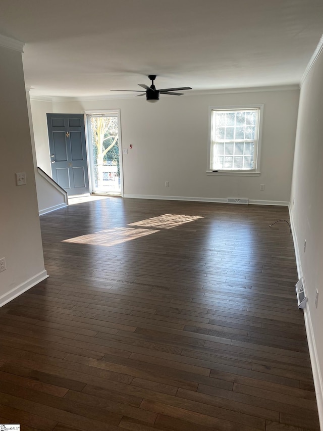 spare room with dark wood-style flooring, visible vents, crown molding, baseboards, and a ceiling fan