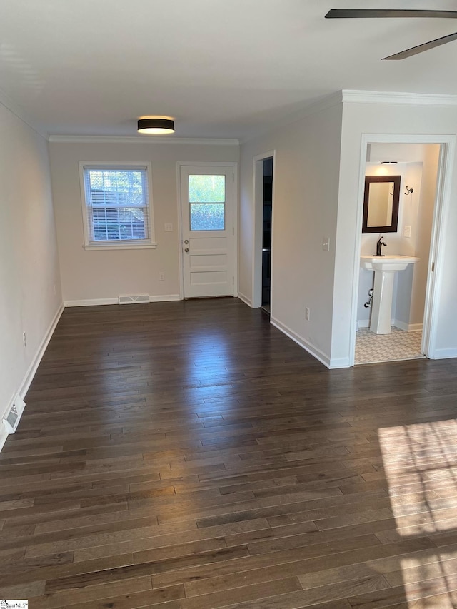 interior space featuring baseboards, visible vents, crown molding, and dark wood-style flooring