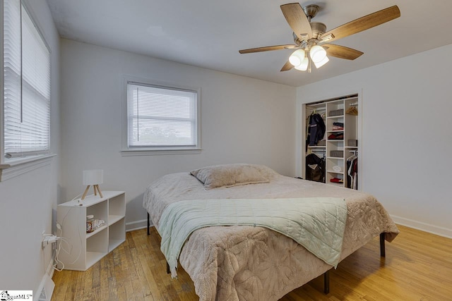 bedroom featuring baseboards, a closet, wood finished floors, and ceiling fan