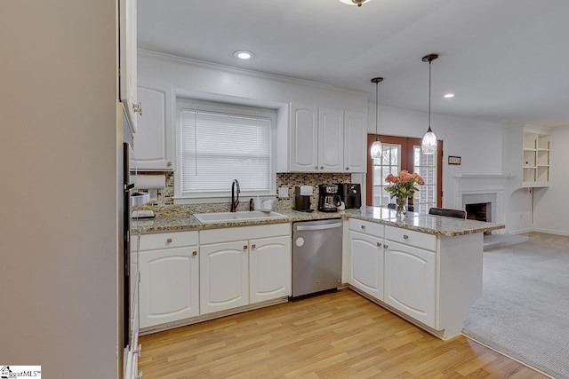 kitchen with a sink, a peninsula, stainless steel dishwasher, open floor plan, and white cabinets