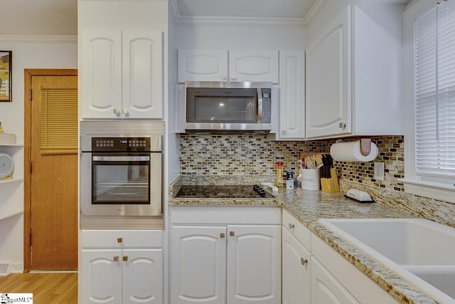 kitchen featuring white cabinetry, crown molding, light wood-type flooring, stainless steel appliances, and a sink