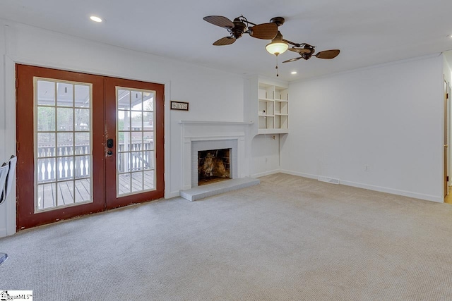 unfurnished living room with french doors, a fireplace, recessed lighting, ceiling fan, and carpet